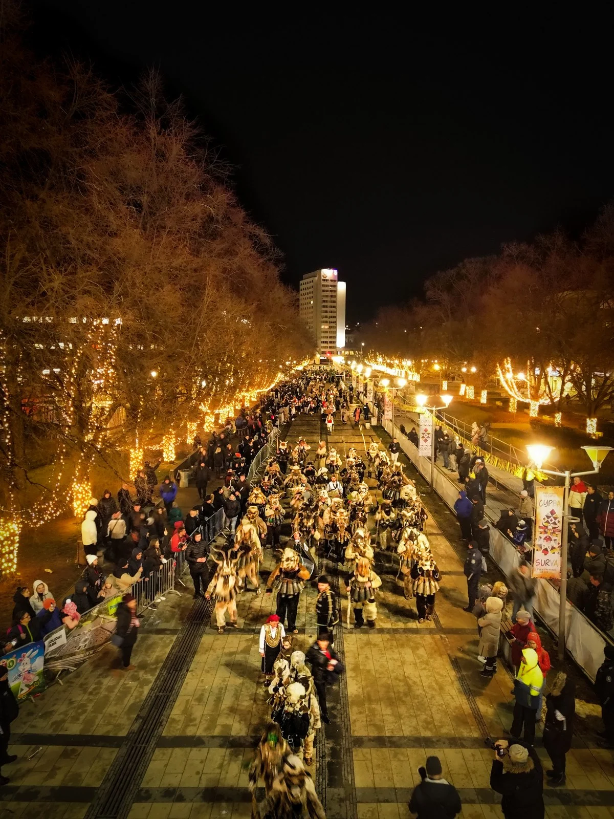 夜のペルニクの仮面祭で、明かりに照らされた通りを進む一団