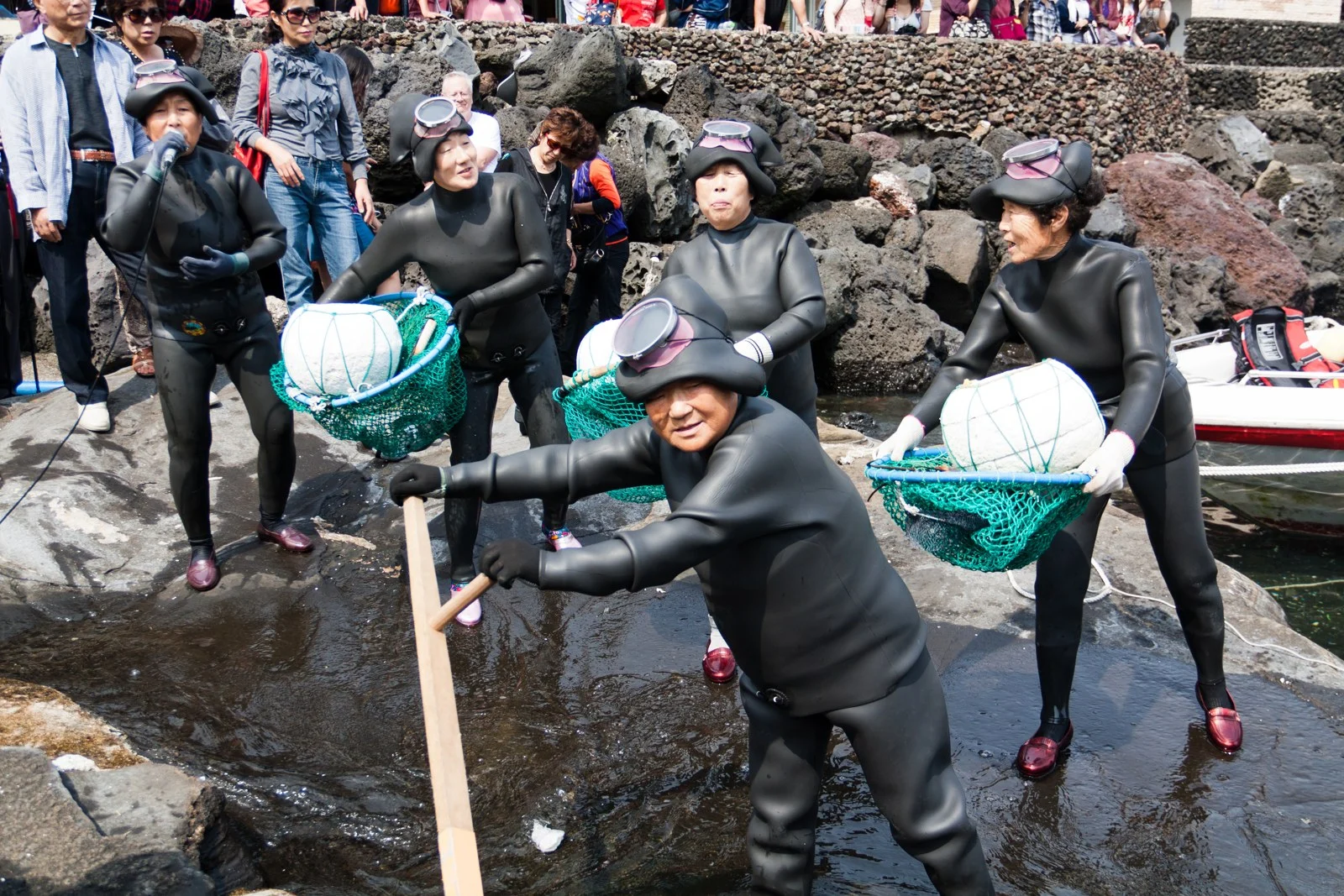 済州島の海岸で潜水具や網を手にして集まる海女たち