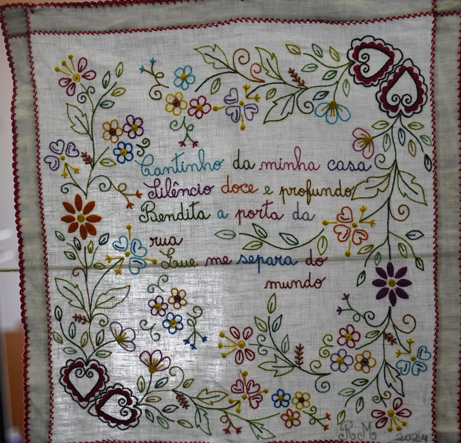花やハートの模様の間にポルトガル語の言葉が刺繍されたハンカチ